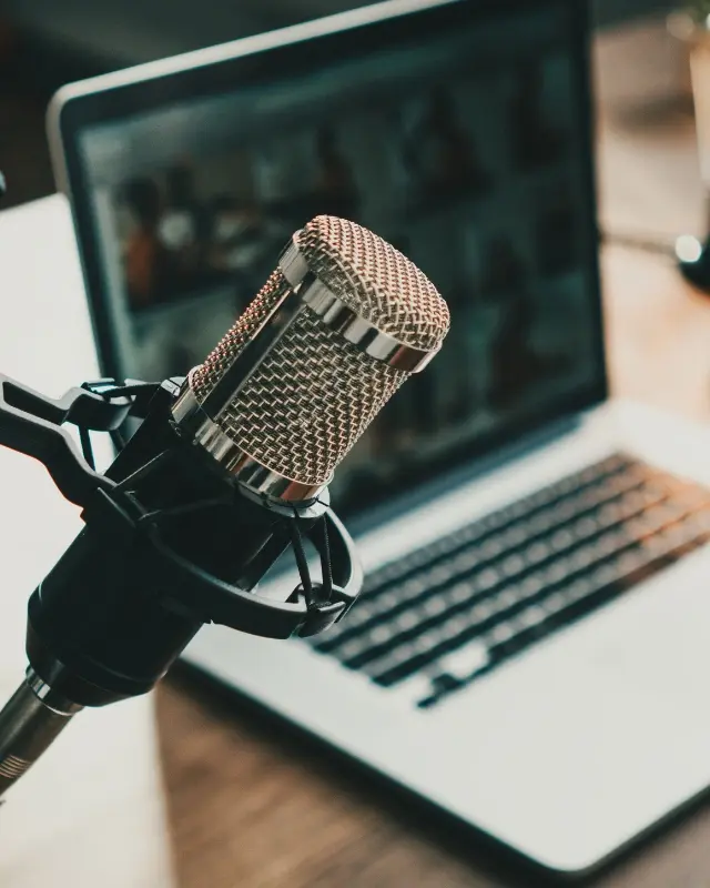 A laptop with a microphone in the forecround, representing the podcast services Christy offers